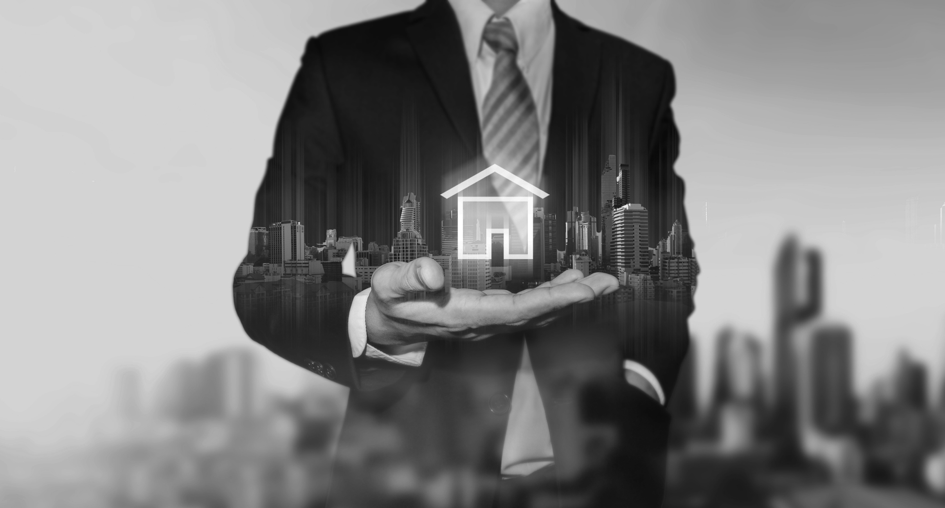 Real estate hero image of open hand holding a digital image of a house with black and white filter